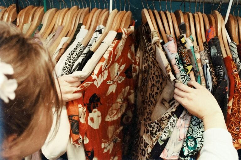 Hands holding vintage clothing on wooden hanger weighing free vs paid listing tools