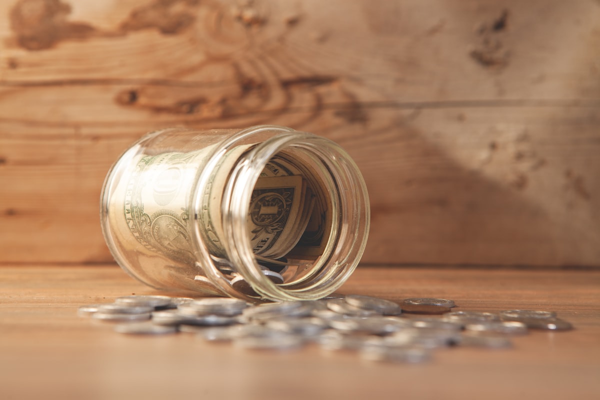 Glass jar of coins on a table representing reselling earnings