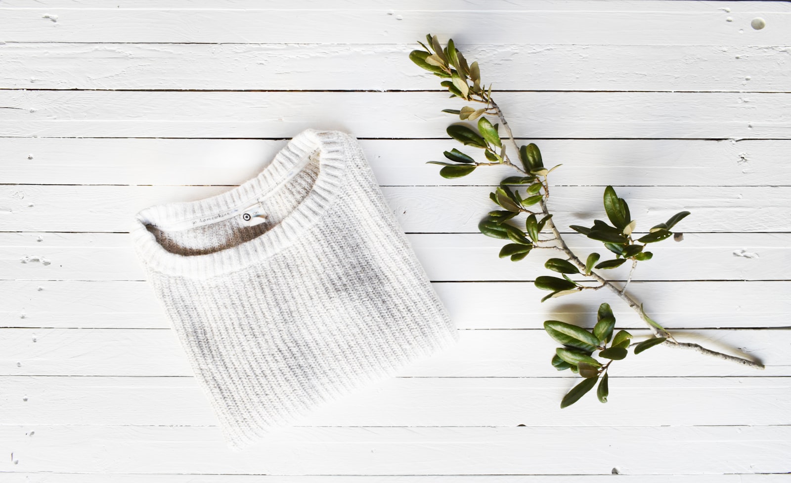 Folded knit sweater laid flat on a white surface