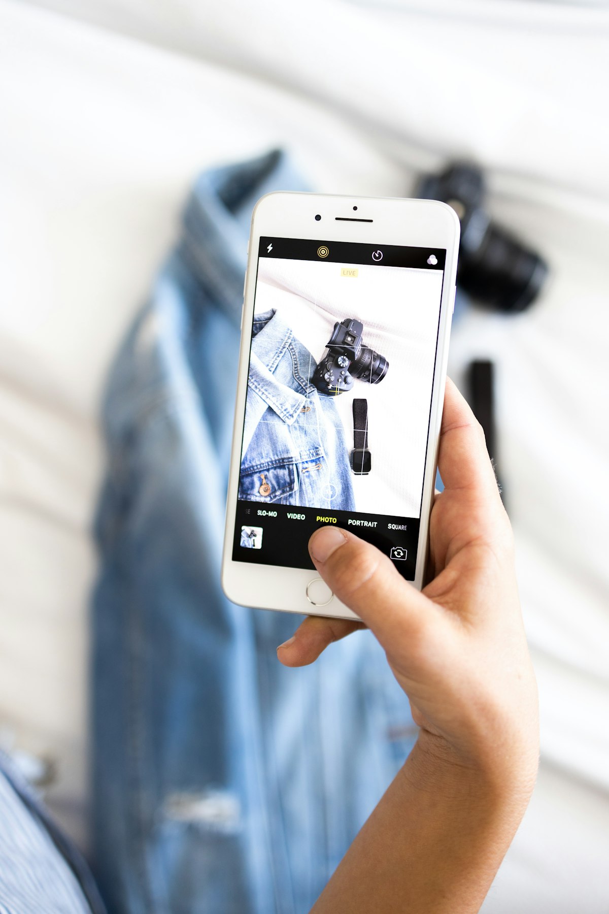 Seller photographing a denim jacket with a smartphone for a listing
