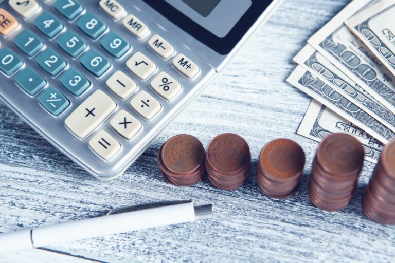 Calculator, pen and coins on a desk for working out reselling profit