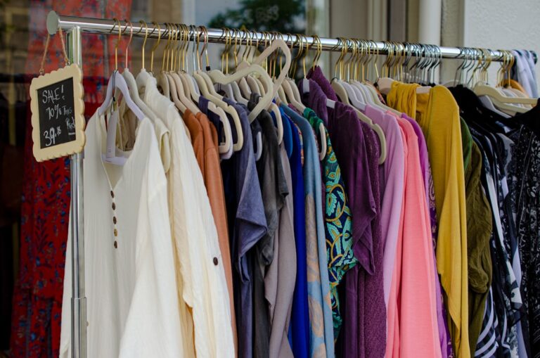 Rack of secondhand shirts organized by color for resale